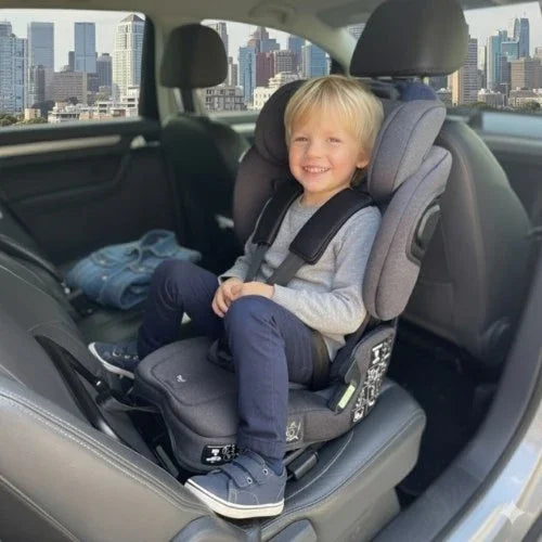 Older boy sitting rear-facing in a TinySeats Two. He has plenty of legroom. In the background we see Singapore downtown