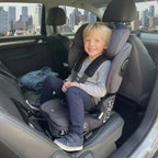 Older boy sitting rear-facing in a TinySeats Two. He has plenty of legroom. In the background we see Singapore downtown